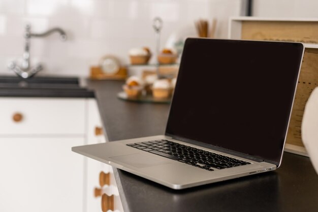 Écran blanc pour ordinateur portable sur table avec fond de cuisine.