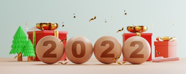 Écran d'impression de l'année 2022 sur des boules en bois avec des coffrets cadeaux et des pins sur la table pour la préparation joyeux Noël et bonne année concept.