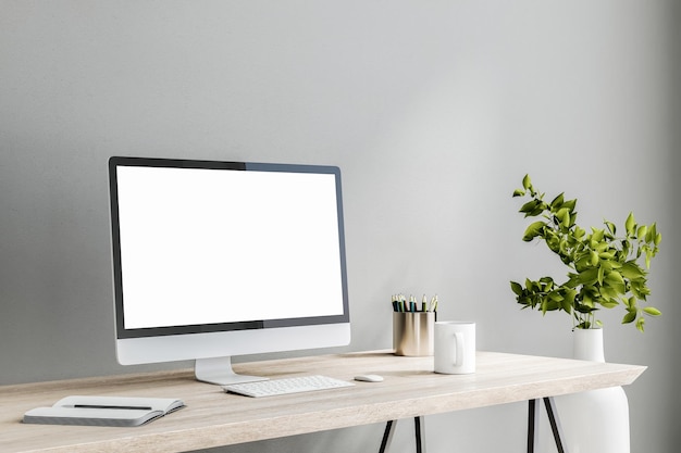 Écran d'ordinateur blanc vierge sur une table en bois clair avec une tasse de thé et un ordinateur portable sur une maquette de rendu 3D de fond de mur gris