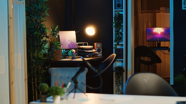 Écran d'ordinateur montrant un rendu d'animation en cours d'exécution dans un intérieur de maison vide et faiblement éclairé 3D sur des écrans numériques en néon éclairé salon d'appartement confortable rempli de plantes d'intérieur