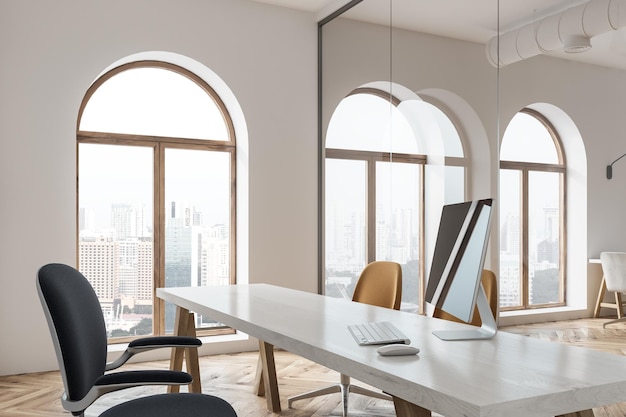 Écran d'ordinateur noir posé sur une table de bureau blanche dans une pièce avec des fenêtres en arc et des murs en verre. maquette de rendu 3d