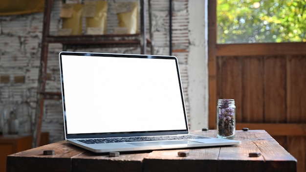 Écran d'ordinateur portable vide sur une table en bois dans un café.