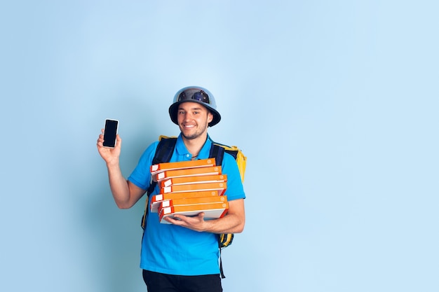 Écran de téléphone vide. Émotions du livreur caucasien isolé sur mur bleu