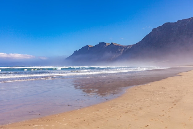 Écran de veille pittoresque de la mer Écume blanche de la mer et des montagnes au loin dans le brouillard