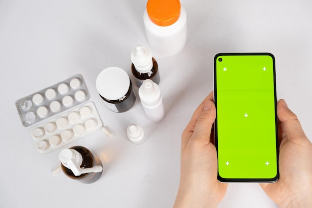 Écran vert clé chromatique smartphone entre les mains du patient ou du médecin et beaucoup de médicaments Instructions d'utilisation des médicaments