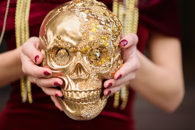 Crâne décoré pour le jour des morts au Mexique avec des paillettes dorées dans les mains d'une femme