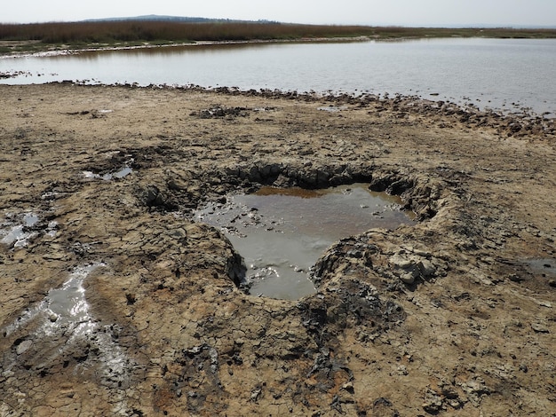 Cratère avec de l'argile de guérison volcanique grise Un trou avec une masse amorphe proéminente des profondeurs de la terre Éruption de boue et de gaz Temryuk Russie Surface du sol fissuré Texture d'une coulée de boue se fissure