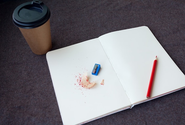 Photo crayon, cahier et tasse à café en papier sur fond de tissu marron