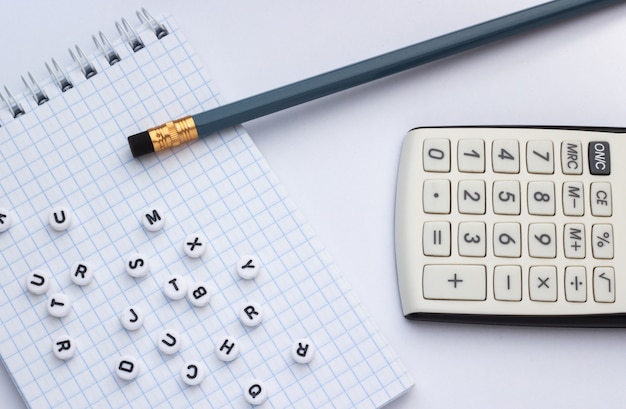 Crayon, calculatrice et cahier à lettres sur fond blanc