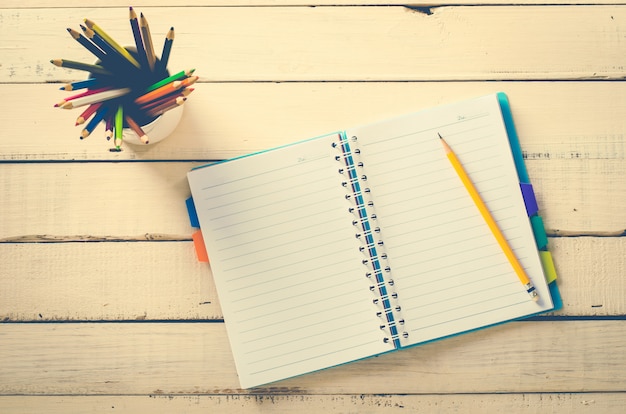 Crayon de couleur et cahier sur la table en bois rugueuse