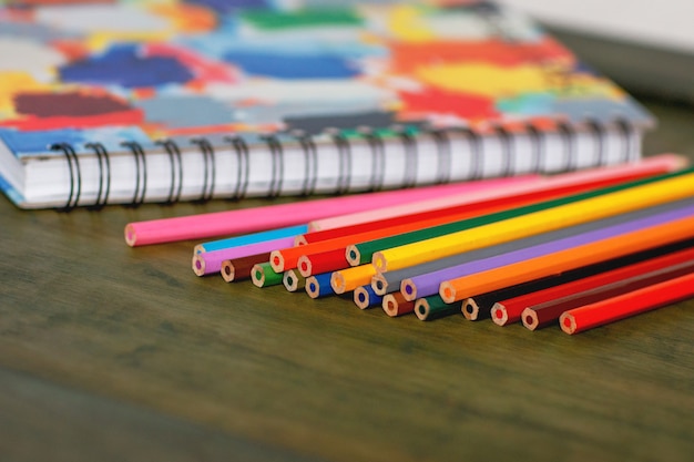 Crayon de couleur et carnet de croquis sur table en bois