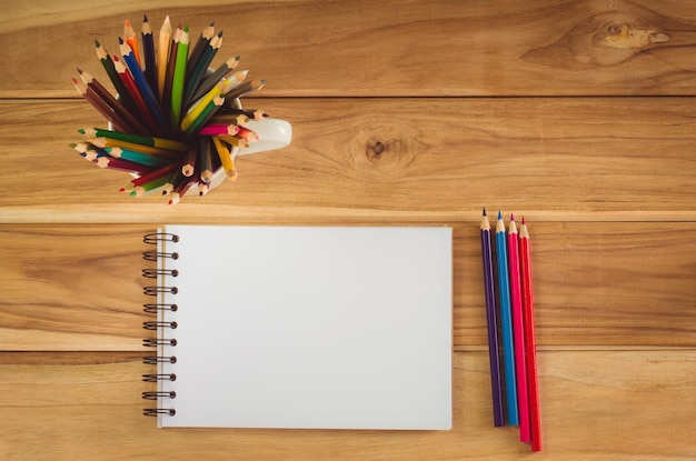 Crayon de couleur et carnet de croquis sur table en bois