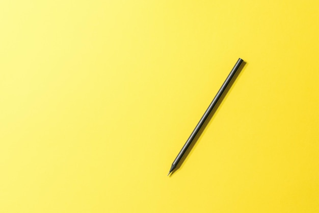 Crayon graphite noir sur fond jaune vif Un outil pour dessiner et écrire