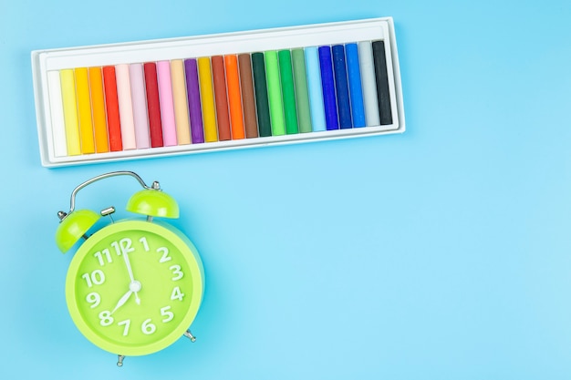 Crayon et horloge verte matin sur fond bleu style pastel avec fond.