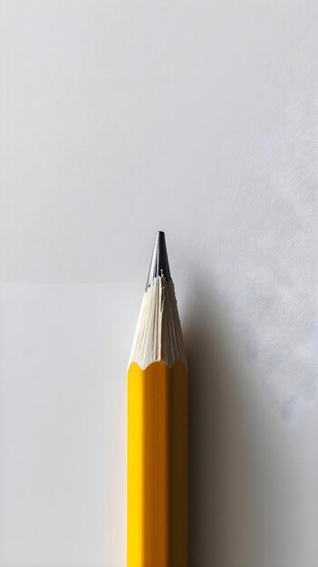 un crayon jaune avec un bout noir sur une surface blanche