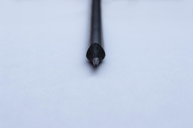 Photo un crayon noir se trouve sur une feuille de papier blanc