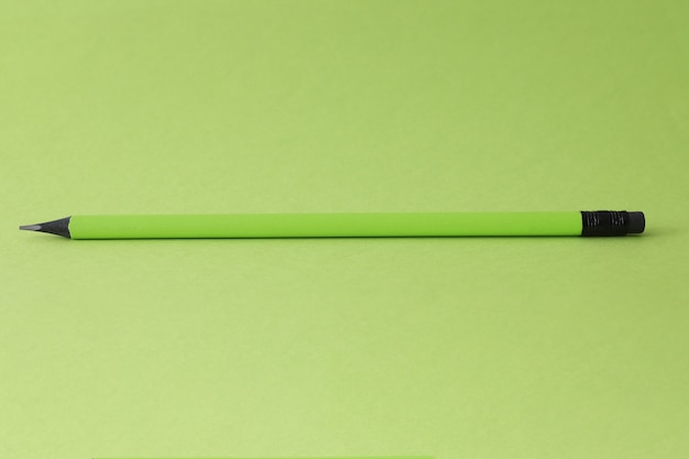 Crayon simple pointu allongé sur fond vert esquisse en gros plan pour le concept d'enfants