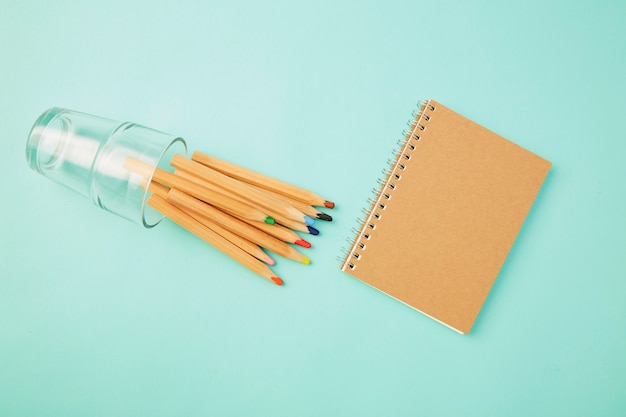 Crayon en verre avec un cahier sur bleu