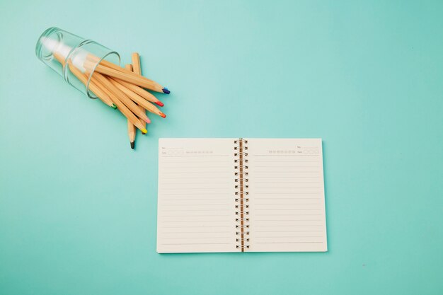 Crayon en verre avec un cahier sur bleu