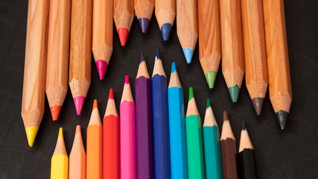 Crayons en bois de couleur différente sur fond de tableau noir