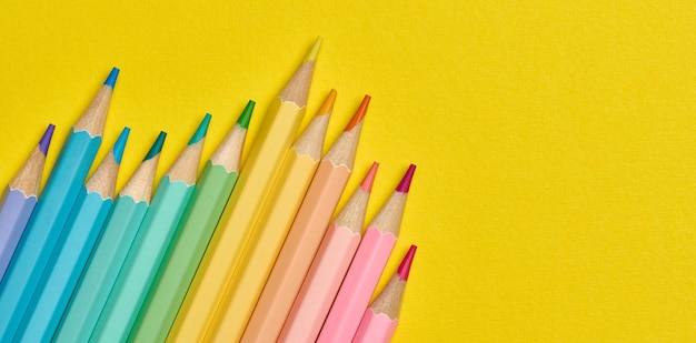 Crayons en bois multicolores sur un fond jaune vue supérieure