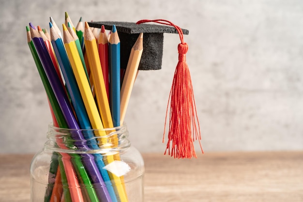 Crayons avec chapeau de graduation dans le concept d'apprentissage de l'éducation en verre