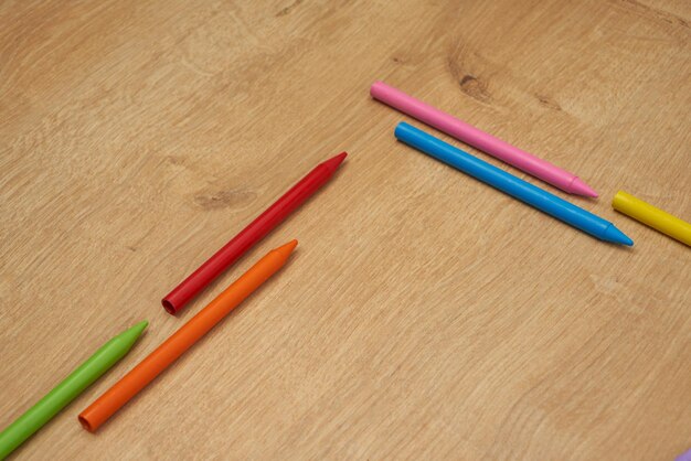 Crayons de cire multicolores pour enfants pour dessiner sur une table en bois.