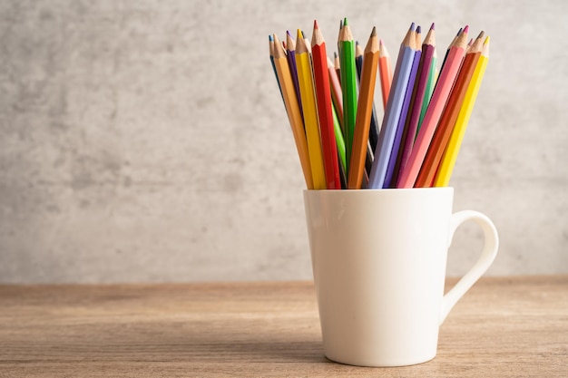 Crayons colorés dans une tasse blanche avec espace de copie apprenant le concept d'enseignement universitaire