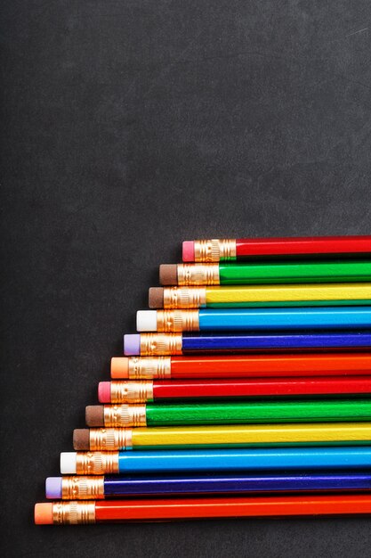 Crayons colorés avec gommes d'affilée sur fond noir