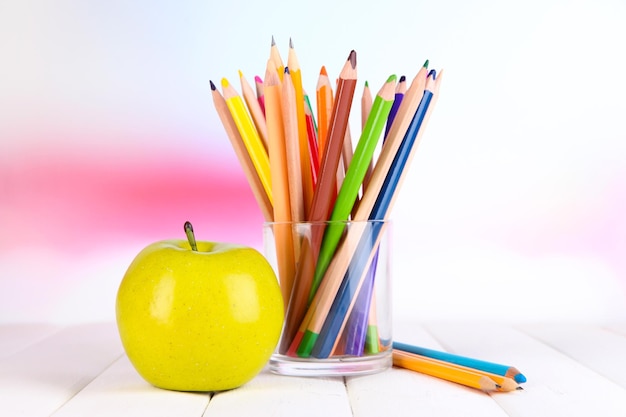 Crayons colorés en verre sur table en bois sur fond clair