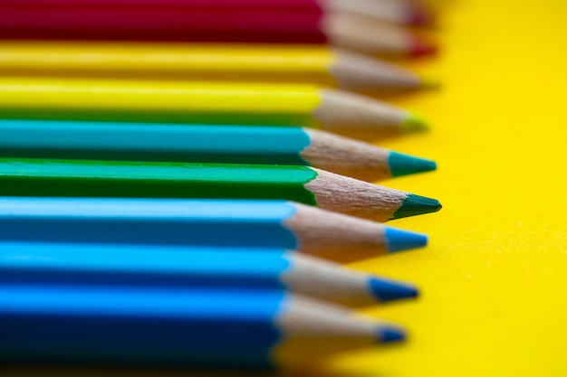 Crayons de couleur aux couleurs de l'arc-en-ciel d'affilée sur fond jaune