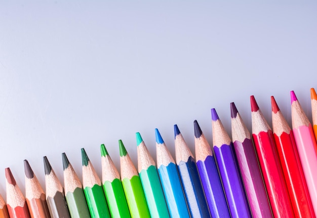 Crayons de couleur de différentes couleurs placés sur fond blanc