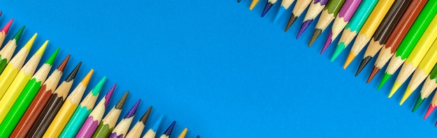 Crayons de couleur de l'école longue bannière de bordure colorée avec espace de copie, fond de bureau bleu, photo vue de dessus