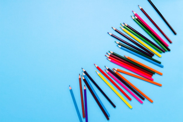 Crayons de couleur éparpillés sur un fond bleu. Mise à plat, vue de dessus