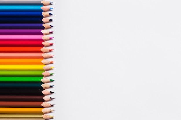 Crayons de couleur et une feuille de papier blanche sur fond blanc