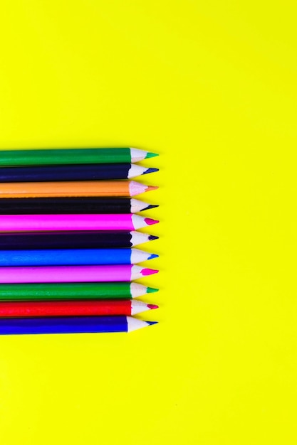 Crayons de couleur sur fond jaune, arrière-plan pour les concepteurs, espace pour le texte