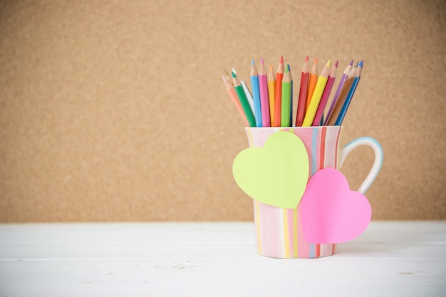 Crayons de couleur nature morte dans une tasse colorée sur une table en bois et affichez-le pour insérer votre texte