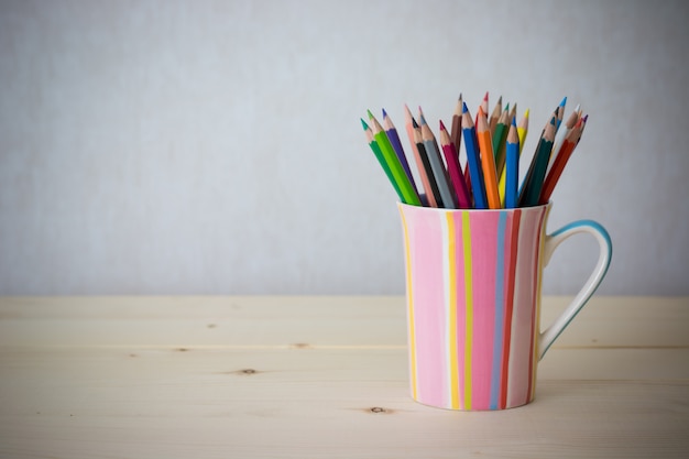 Crayons de couleur nature morte dans une tasse colorée sur une table en bois - photo de style effet vintage