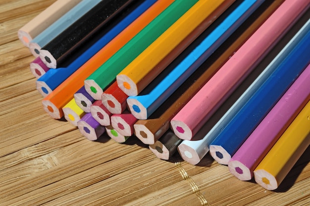 Crayons de couleur non affûtés dans une pile sur une table en bois.