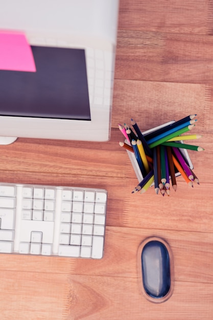 Crayons de couleur en pot par ordinateur au bureau en bois