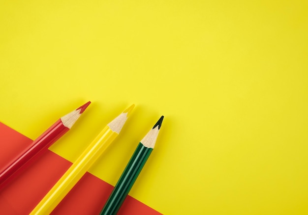 Crayons de couleur rouge, vert et jaune sur fond de papier coloré Concept créatif minimaliste