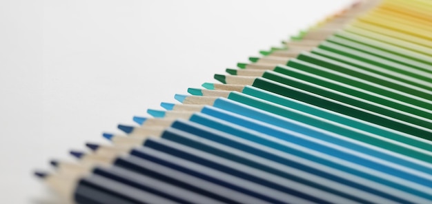 Crayons de couleurs parfaitement disposés en rangée sur une surface blanche macro de crayons pour le dessin