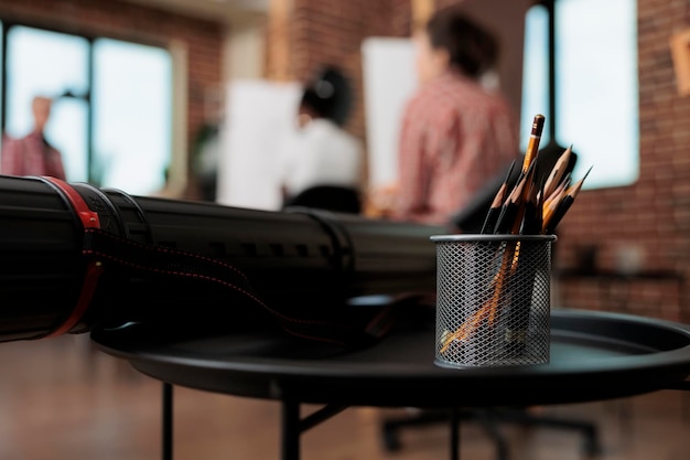 Photo crayons dans un support métallique et un tube de toile sur la table dans un studio d'art moderne outils de dessin et fournitures en classe les gens apprennent à dessiner et à dessiner dans l'enseignement des beaux-arts en groupe