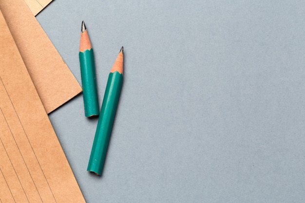 Crayons et feuilles de papier avec bloc-notes sur une table de bureau grise