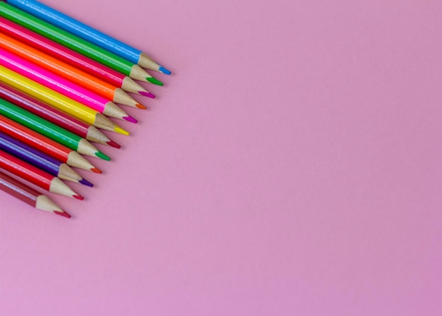 Crayons lumineux colorés sur fond rose avec une copie de l'espace