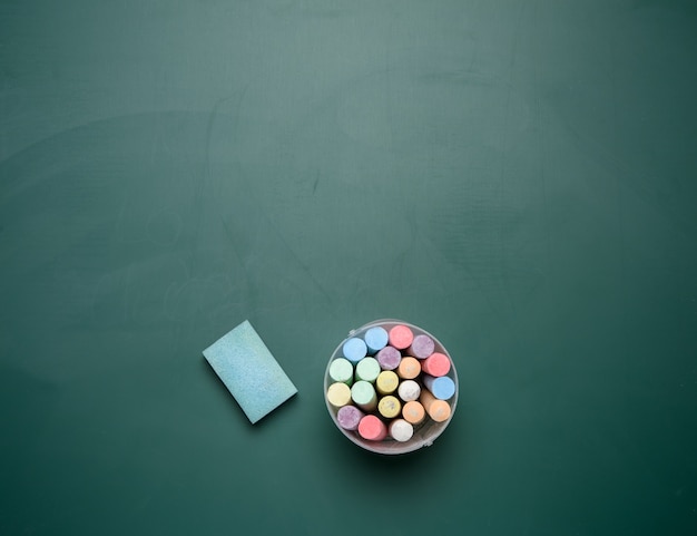 Crayons multicolores sur le fond du tableau noir de l'école de craie verte, espace copie