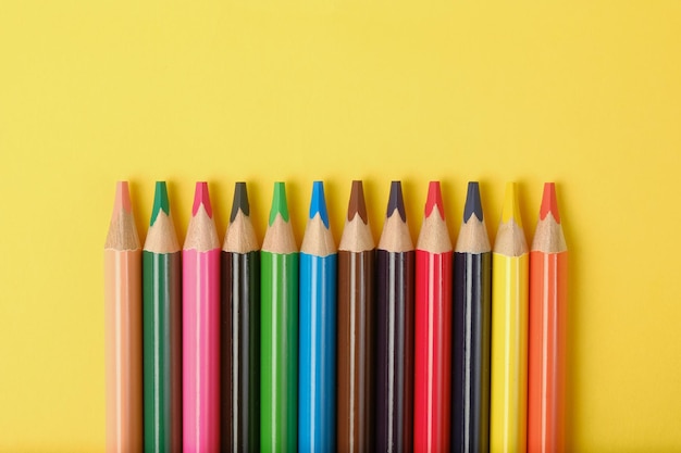 Crayons multicolores sur fond jaune avec une place pour le texte