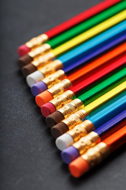 Crayons multicolores pour dessiner et dessiner d'affilée sur un fond noir texturé d'affilée