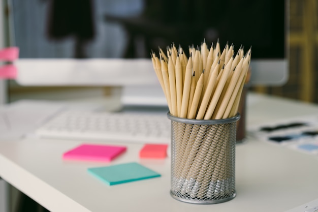 Les crayons sont dans la boîte en filet et placés sur le bureau