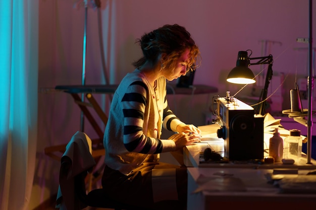 Le créateur de mode en atelier jeune fille couturière utilise une machine à coudre pour créer des vêtements sur mesure